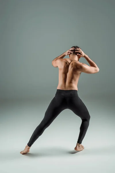 Vista posteriore della ballerina in leggings neri che danza contemporanea su sfondo scuro — Foto stock