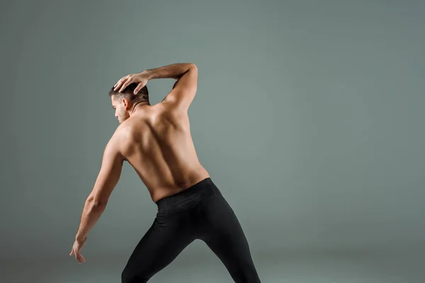 Вид ззаду танцюриста в чорних легінсах танцює сучасний ізольований на сірому — стокове фото