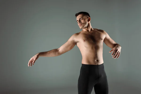 Guapo bailarín con los ojos cerrados en negro leggings bailando contemporáneo aislado en gris - foto de stock