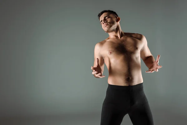 Handsome dancer with closed eyes in black leggings dancing contemporary isolated on grey — Stock Photo