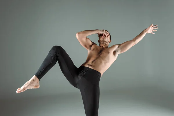 Dancer in black leggings dancing contemporary and obscuring face isolated on grey — Stock Photo