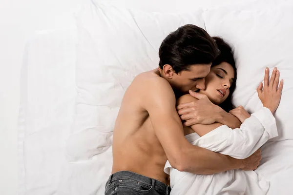 Vista dall'alto del tenero fidanzato che abbraccia la fidanzata sensuale e giace sul letto bianco — Foto stock