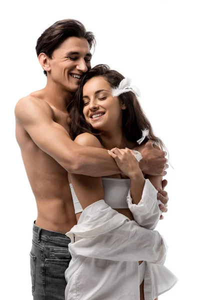 Sonriente pareja abrazándose y divirtiéndose con plumas aisladas en blanco - foto de stock