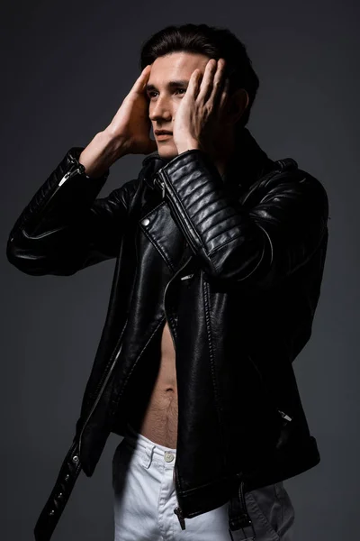 Young sexy man in black leather jacket, isolated on grey — Stock Photo
