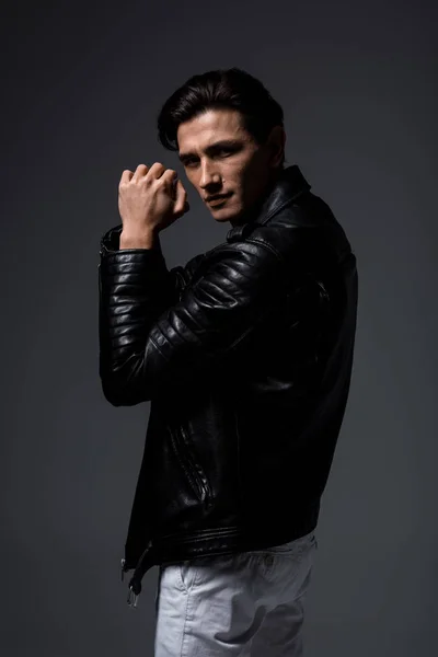 Homem elegante bonito em jaqueta de couro preto, isolado em cinza — Fotografia de Stock