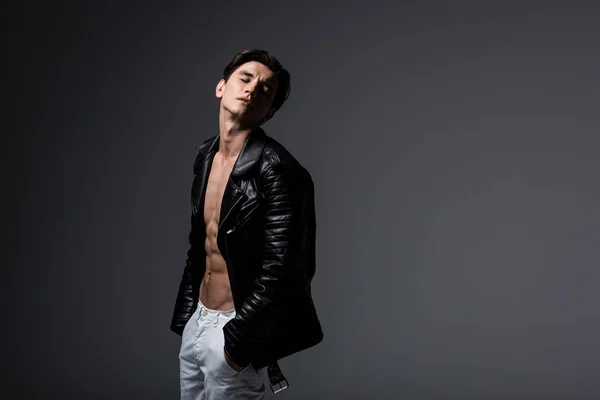 Stylish sexy man in white jeans and black leather jacket, isolated on grey — Stock Photo