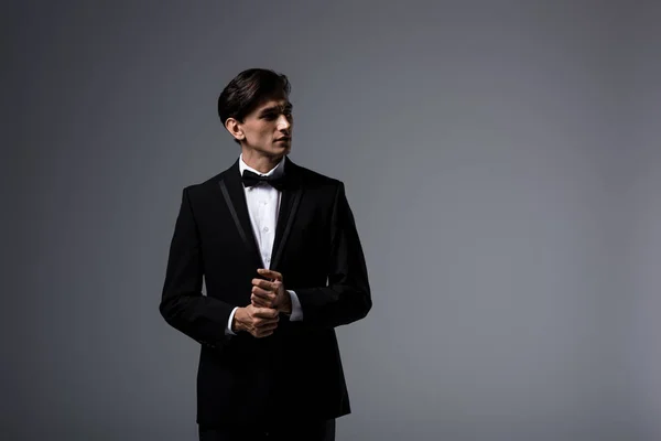 Красивий чоловік стоїть в костюмі і краватці лук, ізольований на сірому — стокове фото