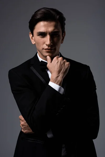 Schöner nachdenklicher Mann in Anzug und Krawattenschleife, isoliert auf grau — Stockfoto