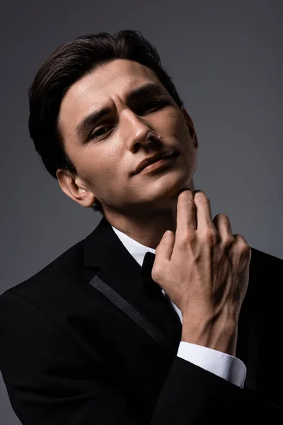 Schöner Mann posiert in Anzug und Krawattenschleife, isoliert auf grau — Stockfoto