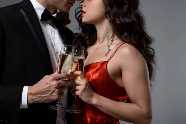 Vue recadrée du couple romantique serrant et tenant des verres à champagne, isolé sur gris — Photo de stock