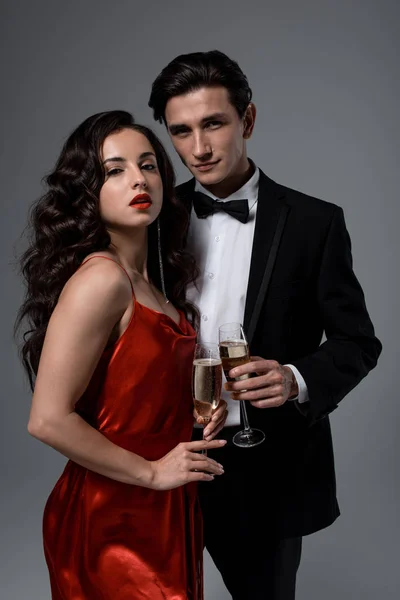 Romantic festive couple holding glasses of champagne, isolated on grey — Stock Photo