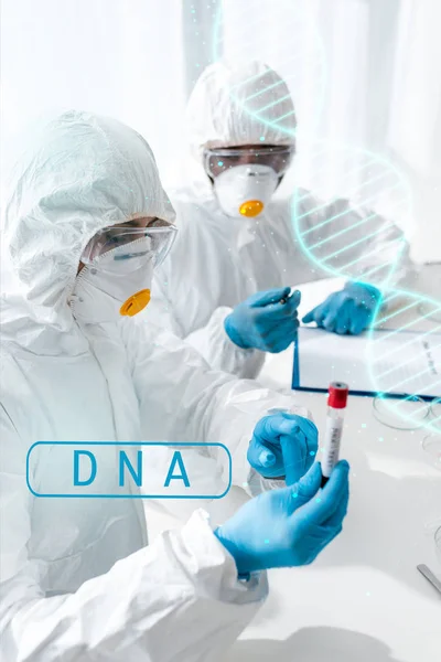 Scienziato che punta il dito e fa il test del DNA e il suo collega afroamericano che guarda l'illustrazione del DNA — Foto stock