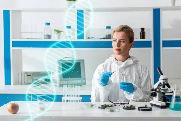 Atractivo biólogo sosteniendo tubo de ensayo y sentado cerca de ilustración de ADN - foto de stock