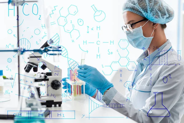 Side view of scientist holding test tube and sitting near formulas illustration — Stock Photo