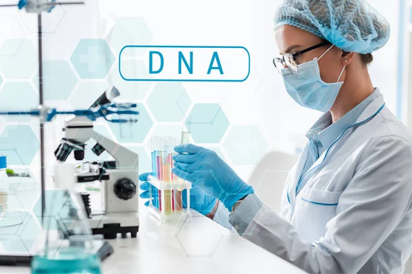 Вид збоку вченого, що тримає пробірку і сидить біля ілюстрації ДНК — стокове фото