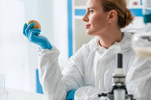 Enfoque selectivo del biólogo sosteniendo manzana entera en el laboratorio - foto de stock