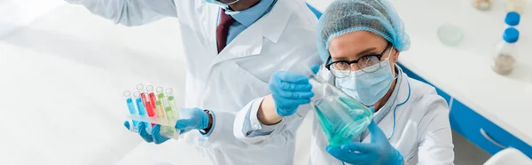 Panoramic shot of multicultural biologists doing test in lab — Stock Photo