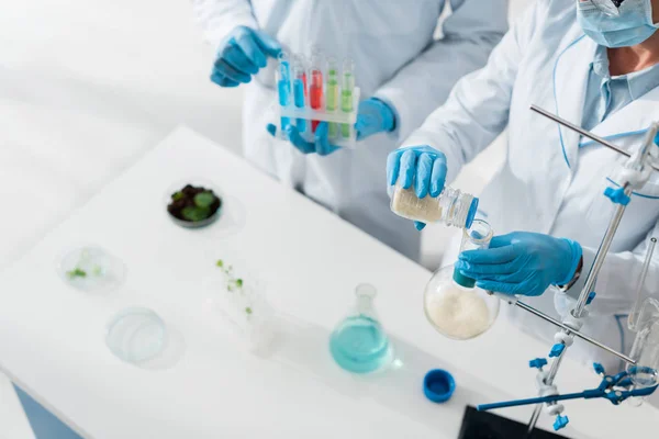 Vista recortada de biólogos con batas blancas haciendo pruebas en laboratorio - foto de stock