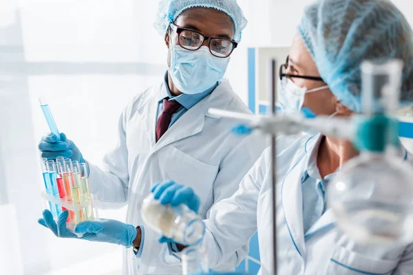 Enfoque selectivo de biólogos multiculturales haciendo pruebas en laboratorio - foto de stock