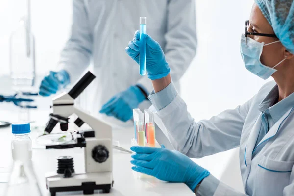 Enfoque selectivo del biólogo que mira el tubo de ensayo en el laboratorio - foto de stock