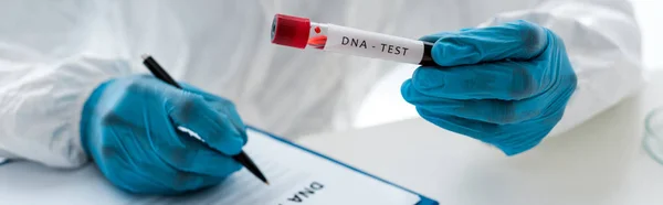 Panoramic shot of scientist writing and holding test tube with lettering dna test — Stock Photo