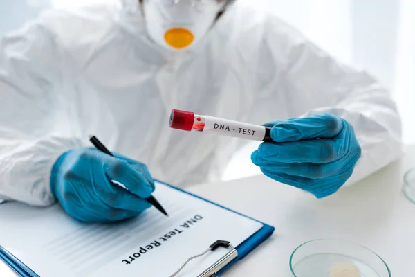 Cropped view of scientist writing and holding test tube with lettering dna test — Stock Photo