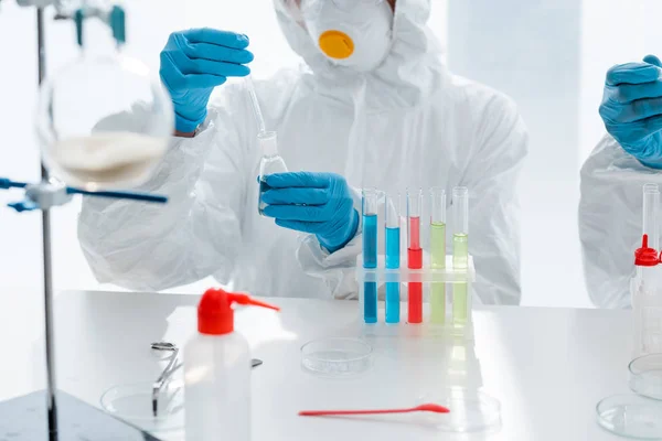 Обрезанный вид ученых в латексных перчатках, делающих тест ДНК в лаборатории — стоковое фото