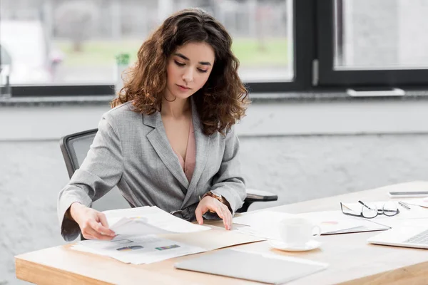 Atractivo gerente de cuenta sentado en la mesa y haciendo papeleo - foto de stock