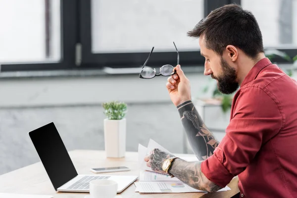 Schöner Kontoverwalter sitzt am Tisch und hält eine Brille — Stockfoto