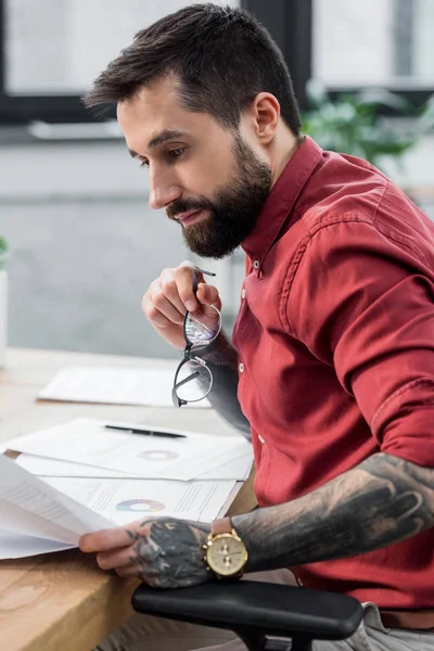 Beau gestionnaire de compte assis à table et faisant de la paperasse — Photo de stock