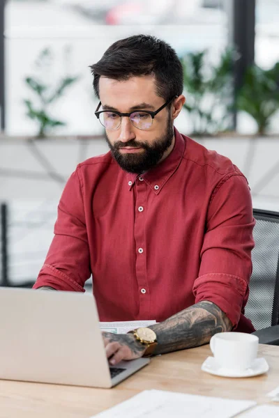 Handsome account manager sitting at table and using laptop — Stock Photo