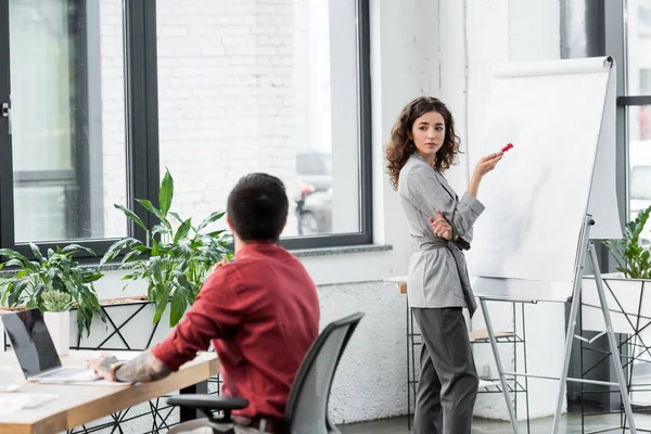 Account manager standing near flipchart and talking with colleague — Stock Photo