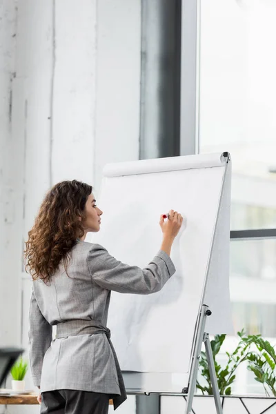 Attractive account manager writing on flipchart in office — Stock Photo