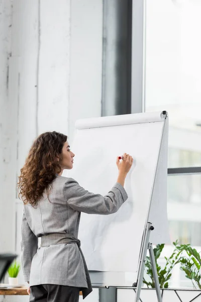 Attraktiver Kontoverwalter, der im Büro auf Flipchart schreibt — Stockfoto