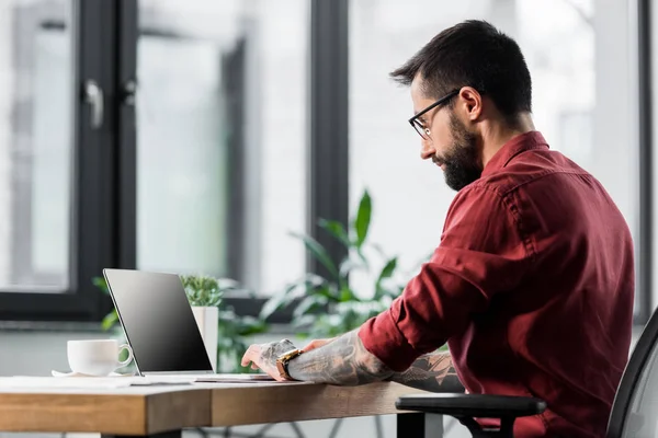 Beau gestionnaire de compte assis à table et utilisant un ordinateur portable — Photo de stock