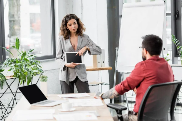 Gestor de cuentas de enfoque selectivo apuntando con el dedo a la tableta digital y hablando con su colega - foto de stock