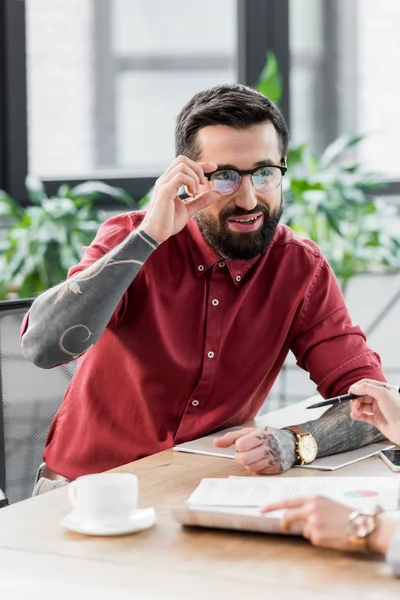 Lächelnder Kontoverwalter mit Brille blickt seinen Kollegen an — Stockfoto