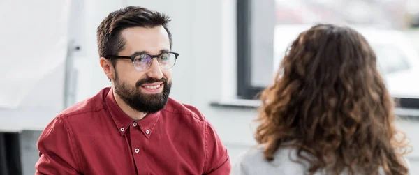 Plano panorámico de gerente de cuenta sonriente mirando a colega - foto de stock