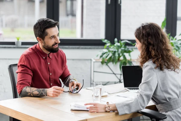 Account manager sorridenti seduti a tavola e che parlano in ufficio — Foto stock