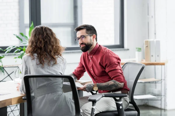 Gerentes de cuenta hablando y sentado en la mesa en la oficina - foto de stock