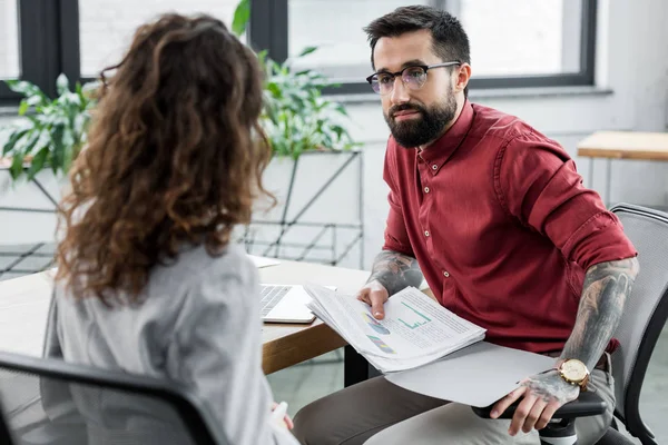 Selective focus of account manager holding papers and talking with colleague — Stock Photo