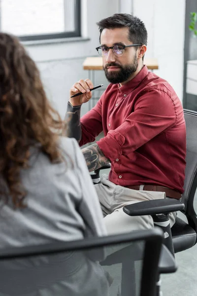 Enfoque selectivo del administrador de cuentas sentado y mirando a su colega - foto de stock