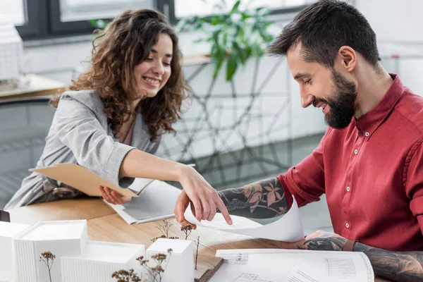 Sorridenti architetti di realtà virtuale che puntano il dito contro le cianografie e fanno scartoffie — Foto stock