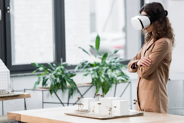 Side view of virtual reality architect in virtual reality headset looking at model of house — Stock Photo