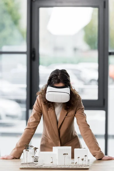 Virtual reality architect in virtual reality headset looking at model of house — Stock Photo