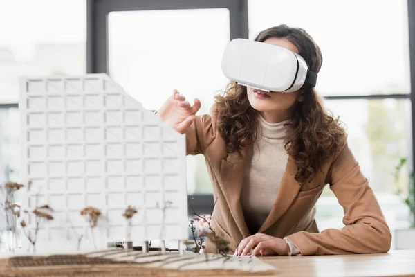 Virtual reality architect in virtual reality headset looking at model of house — Stock Photo