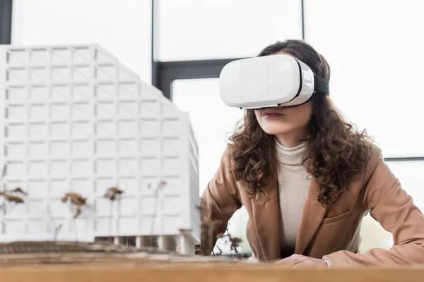 Virtual reality architect in virtual reality headset looking at model of house — Stock Photo