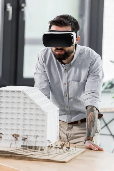 Архітектор віртуальної реальності в гарнітурі віртуальної реальності дивиться на модель будинку — стокове фото