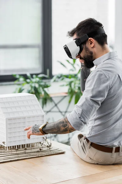 Virtual reality architect in virtual reality headset looking at model of house — Stock Photo