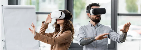 Panoramic shot of virtual reality architects in virtual reality headsets — Stock Photo